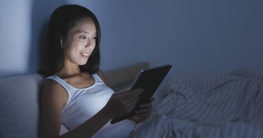 Yatakta tablet bilgisayarda çalışan kadın 