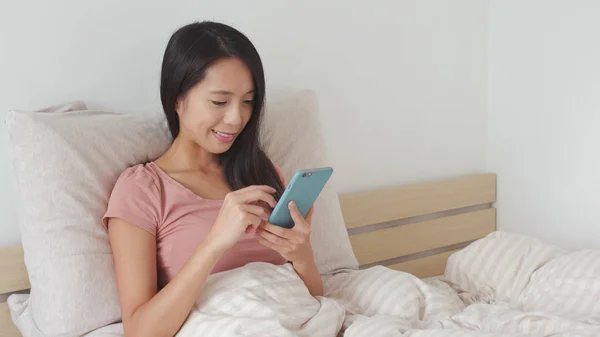 Woman using mobile phone on bed — Stock Photo, Image