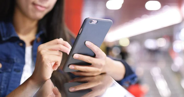 Kvinna med hjälp av mobiltelefon i station — Stockfoto