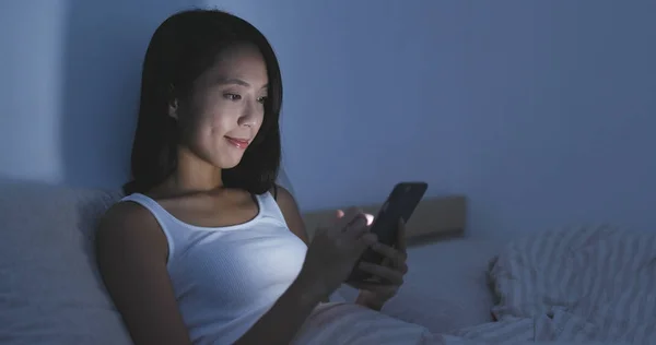 Mujer mirando el celular en la cama —  Fotos de Stock