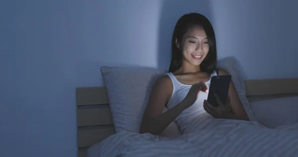 Wanita menggunakan ponsel di tempat tidur di malam hari — Stok Foto
