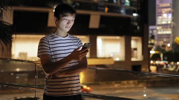 Человек, использующий мобильный телефон в городе ночью — стоковое фото