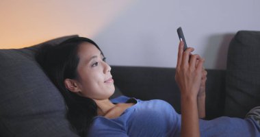 Gece kanepede cep telefonu kullanan kadın 