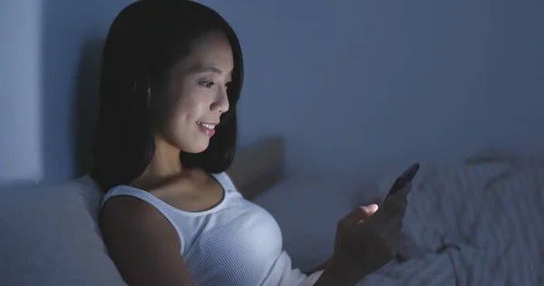 Mujer usando celular en la cama por la noche —  Fotos de Stock