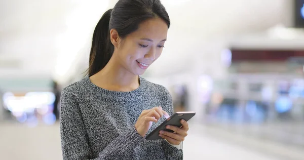 Vrouw met behulp van mobiele telefoon in luchthaven — Stockfoto
