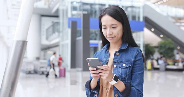 Vrouw met behulp van mobiele telefoon in luchthaven — Stockfoto