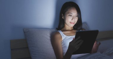 Yatakta tablet bilgisayarda çalışan kadın 