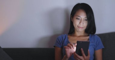 Gece kanepede cep telefonu kullanan kadın 