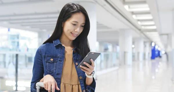 Vrouw lopen in de luchthaven en controleren op mobiele telefoon — Stockfoto