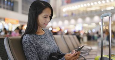 Havaalanında cep telefonu üzerinde çalışan kadın 