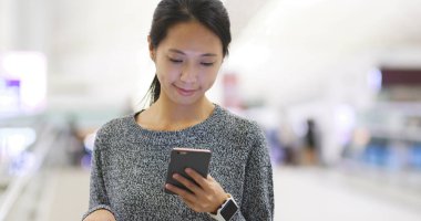 Havaalanında cep telefonu üzerinde çalışan kadın 