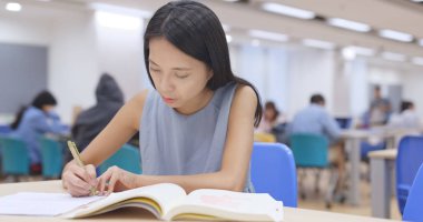 Kütüphanede ödevini üzerinde çalışma öğrenci 