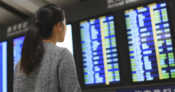 Woman looking at the flight display board