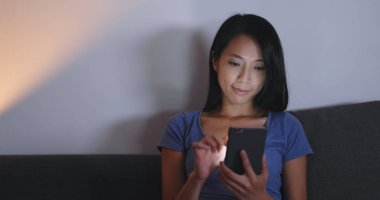 Evde cep telefonu kullanan bir kadın 