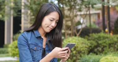 Parkta akıllı telefon kullanan kadın.