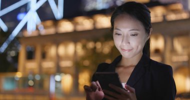 Gece şehirde akıllı telefon kullanan bir kadın. 