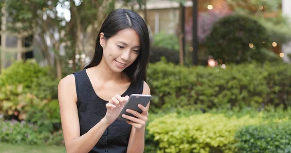 Vrouw die werkt op mobiele telefoon in het park — Stockfoto