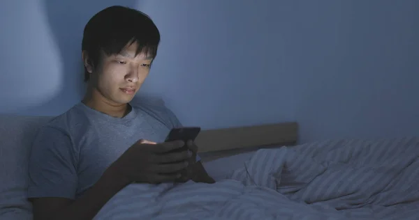 Asiatico uomo utilizzando cellulare su letto — Foto Stock