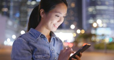 Kadın sokakta cep telefonu bakarak 