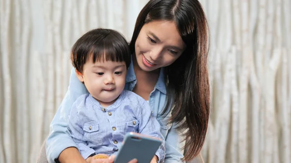 Мать показывает что-то на смартфоне своего ребенка — стоковое фото