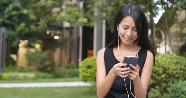 女人在公园里听手机音乐 — 图库照片