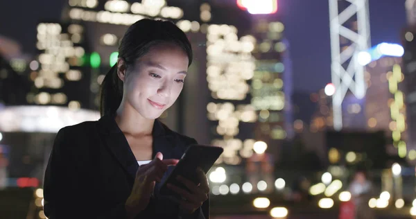 Kobieta za pomocą smartfona w miasto w nocy — Zdjęcie stockowe