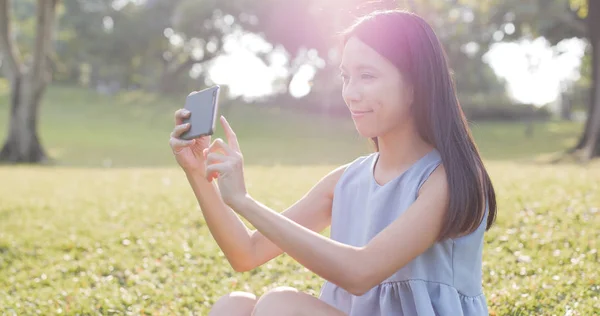 Kvinnan tar foto av mobiltelefon i parken — Stockfoto