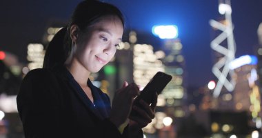 Gece şehirde akıllı telefon kullanan bir kadın. 