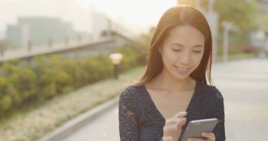 Günbatımı altında cep telefonu kullanan kadın