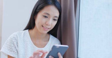 Evde cep telefonu kullanan bir kadın