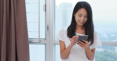 Evde akıllı telefon kullanan bir kadın.