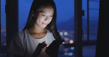 Geceleri cep telefonu kullanan bir kadın.