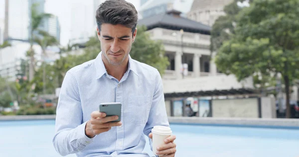 Empresário usando celular com seu café — Fotografia de Stock