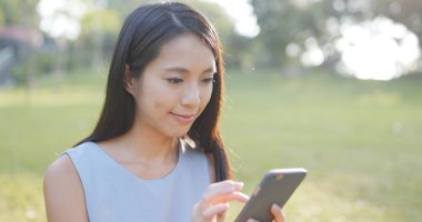 Parkta akıllı telefon kullanan kadın.