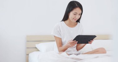 Tablet yatakta izlerken kadın