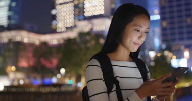 Gece şehirde akıllı telefon kullanan bir kadın.