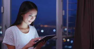 Geceleri alışveriş için tablet bilgisayar kullanan kadın