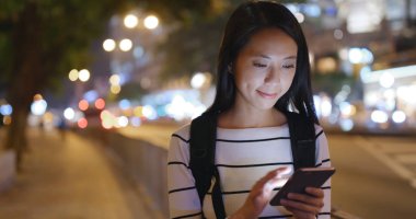 Gece şehirde akıllı telefon kullanan bir kadın.