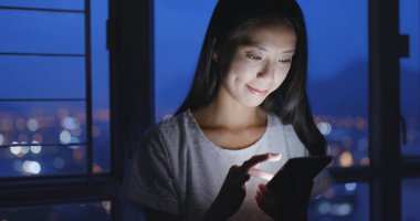 Gece akıllı telefon kullanan bir kadın.