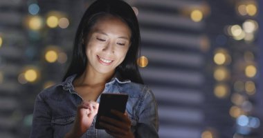 Geceleri cep telefonu kullanan kadın 