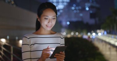 Geceleri cep telefonu kullanan bir kadın.