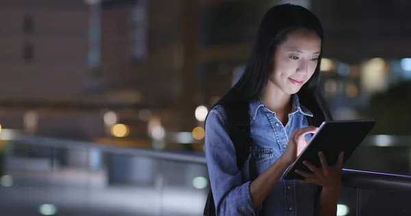 Woman using tablet computer in city at night