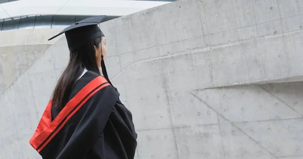 Back of Asian Woman with graduation gown think of future