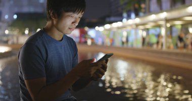 Geceleri cep telefonu kullanan adam.