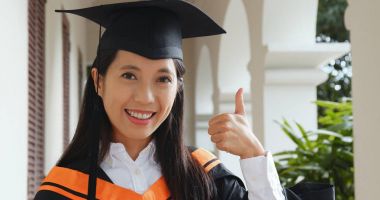 Kadın mezun ve başparmak sırıtmak 