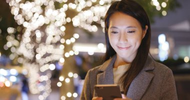 Gece Noel dekorasyonu cep telefonu kullanan kadın