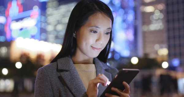 Businesswoman using mobile phone in city at night