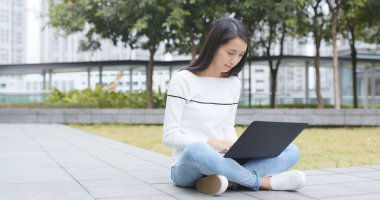 Asyalı kadın iş dizüstü bilgisayar ve cep telefonu kullanma 