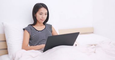 Dizüstü bilgisayarda çalışarak ve yatakta yatarken kadın 