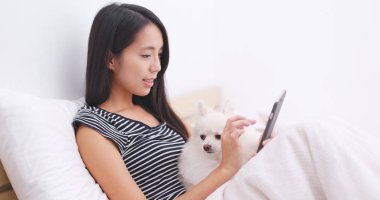 Cep telefonu köpeğini arıyor ve yatağın üstüne oturan kadın 